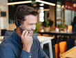 © Wavebreak Media - Mid-adult man speaking over headset at modern open-plan office desk, smiling brightly, copy space