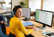 © Wavebreak Media - Man sitting at desk in open-plan office, wearing headset and using dual monitors for spreadsheets