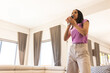 © Wavebreak Media - Teenage girl singing into handheld microphone in living room with sofa, gray curtains, copy space