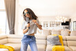 © Wavebreak Media - Woman singing into hairbrush microphone in modern living room with sunglasses and sofa, copy space