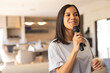 © Wavebreak Media - Woman speaking into black handheld microphone in open-plan kitchen-dining area, with pendant lights