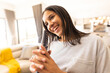 © Wavebreak Media - Young adult multiracial woman smiling while holding television remote control in modern living room