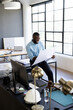 © Wavebreak Media - African American man examining blueprints in modern design office, with hard hat and desk lamp