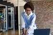 © Wavebreak Media - African American woman leaning over desk in office, smiling at laptop with sticky notes