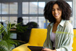 © Wavebreak Media - Woman smiling using tablet on yellow couch in office lounge with glass partition, copy space