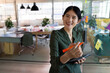© Wavebreak Media - Asian woman writing on glass board in open-plan office using tablet and orange marker, copy space
