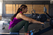 © Wavebreak Media - Woman rowing on machine with digital monitor display in gym cardio area, with natural light shining