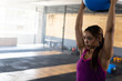 © Wavebreak Media - Woman lifting medicine ball overhead in CrossFit gym with squat rack and kettlebells, copy space