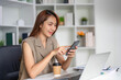 © wichayada - Communication and Technology. A young woman engaged in mobile communication while enjoying coffee in her organized workplace.