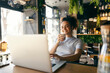 © Dusan Petkovic - Portrait of young interracial freelancer sitting in coffee shop, drinking coffee and typing on laptop.