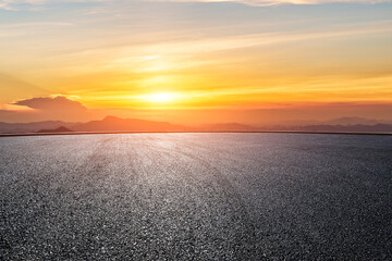 Wall Mural - asphalt road with orange sunset sky and mountain silhouette