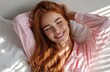 © Kien - a woman with long red hair, smiling and stretching in bed under bright sunlight, wearing a pink shirt and white sheets