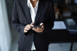 © Wanda - Asian businesswoman in suit standing using smartphone checking email