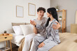 © Pixel-Shot - Happy young couple with pregnancy test sitting in bedroom