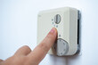 © kittyfly - Thermostat adjustment, Hand adjusting thermostat, home temperature control, energy efficiency, heating system, climate control