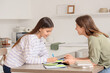 © Pixel-Shot - Teenage girl studying Math with tutor at table in kitchen