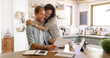 © peopleimages.com - Home, hug and couple with documents, smile and payment for mortgage, rent and love. Apartment, finance and man with woman in kitchen, embrace and paperwork report for savings and investment growth