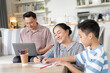 © winnievinzence - Asian grandmother helping grandson doing homework while grandfather working with laptop at home. Family spending time on weekend together