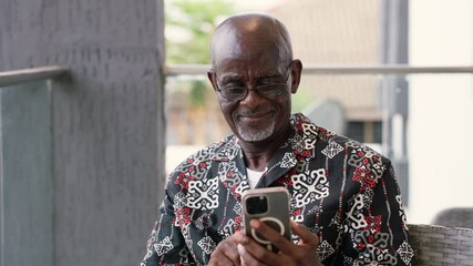 Elderly African man uses his smartphone for internet banking sending money.
