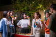 © Wasana - A group of people are gathered around a table with food and drinks