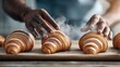 © Denis - Baker preparing freshly baked croissants in a cozy kitchen setting early in the morning with steam rising