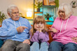 © Andrii Iemelianenko - Irritated grandfather and grandmother scolding granddaughter for bad behavior and disobedience on sofa, raising voice, scream at little grandchild. Difficulties of upbringing, misbehaved child concept