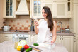© kazakova0684 - Smiling woman using smartphone while preparing fresh vegetable salad in cozy kitchen. Healthy lifestyle, home cooking and online recipe inspiration