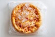 © whitestorm - Frozen pizza in plastic packaging, covered with ice crystals, ready to be cooked, offering a convenient and quick meal option for busy individuals.