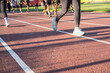 © InveStock - Runners exercising on an outdoor athletics track under the sunlight, focusing on fitness and teamwork. Focus on individuals training together, promoting health, fitness, and collaboration