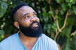 © Wavebreak Media - Looking African American man gazing upward in backyard garden, with green foliage, copy space