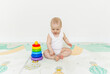 © inna717 - A 5-7 month old baby sits on the floor and plays with bright toys in his room.