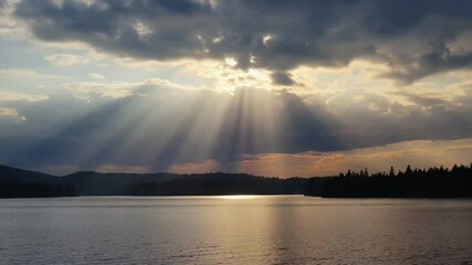Poster - Sunbeams piercing through clouds above a calm lake.

