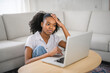 © Louis-Paul Photo - Young woman sitting on floor by the couch using laptop. Afemale working on laptop computer at home.