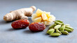 © Nataliia - Ayurvedic ingredients including ginger, dates, cardamom pods and candied pineapple on gray stone background. Close-up