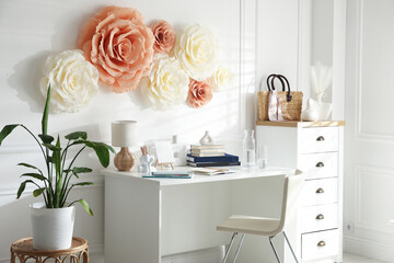 Poster - Beautiful decorative paper flowers on white wall and stylish furniture indoors