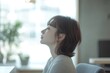 © Sena - A young woman with short brown hair sits by a window, lost in thought, serene and peaceful.