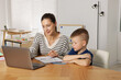 © New Africa - Cute boy and teacher with laptop at desk in school
