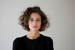 © SuzeO - natural beauty portrait, a self-assured young woman with curly hair and minimal makeup poses in soft studio lighting against a neutral backdrop