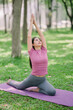 © PSG - Asian woman in pink dress doing yoga, Downward facing dog pose or Adho Mukha Svanasana. A young woman breathing calmly and healthily is meditating with yoga in a park.