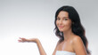 © Buyanskyy Production - Portrait of a young woman with dark hair and clear skin, holding her hand up as if presenting something, against a clean white background. Perfect for advertising, beauty, and lifestyle concepts.