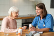 © zinkevych - Female doctor caring for senior patient giving assistance with medication and treatment