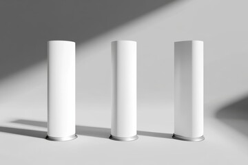 Fototapete - Three cylindrical white stands in a softly lit room, perfect for showcasing products or artwork in a clean and modern presentation.