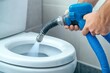 © Yuliia - Plumber utilizes hydro jetting to clear a toilet blockage in a residential bathroom.
