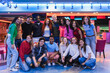 © Koldo_Studio - Happy multi ethnic friends posing together, having fun at the bowling alley and arcade video game room
