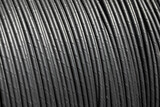 Close-up of thick black cable coil with visible grooves and shadows. Industrial wire texture.