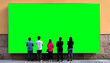 © SdStockgrapher - A group of five people stands in front of a large green screen billboard (chroma key enabled) mounted on a wall, appearing to observe or interact with the blank display.Insert your image chromakeying