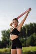 © rostyslav84 - Athletic girl in sportswear doing exercises with fitness rubber bands outdoors in the park