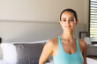 © Wavebreak Media - Smiling woman wearing teal tank top standing in modern bedroom, with bed, lamp, blinds