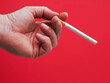 © mark_gusev - Hand holding a cigarette. Red color background shows danger of tobacco product consumption. Unhealthy habit.