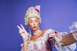 © deagreez - Elegant woman in antique costume making funny expression against purple background.